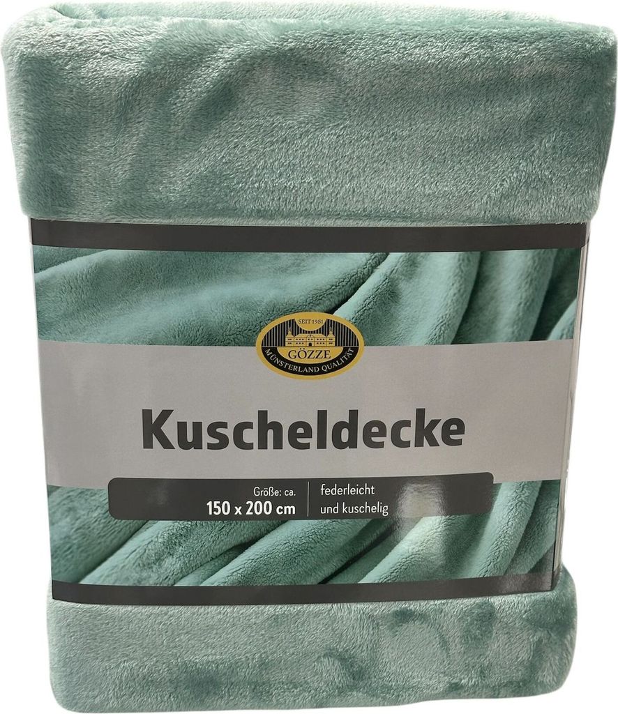 A folded aqua-colored blanket is presented on a light gray background, with a label wrapped around it.