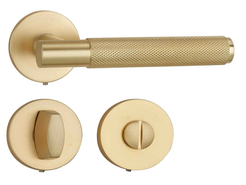A set of golden matte door hardware, including a lever handle, a WC lock mechanism, and a key escutcheon, displayed against a white background.