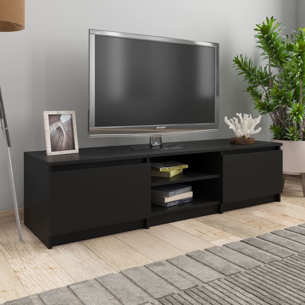A black TV stand with a television on top, placed in a living room setting with a plant and a rug.