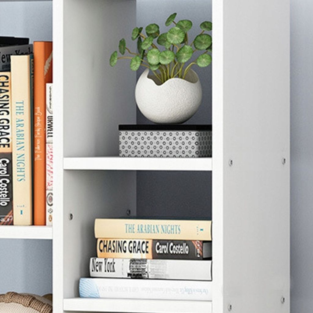 A close-up view of a white bookshelf with several books and a potted plant.