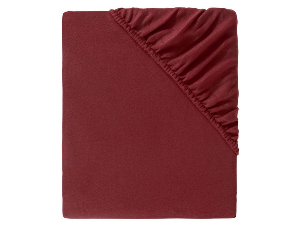 A close-up view of a red fitted sheet, folded to show the elasticized corner.