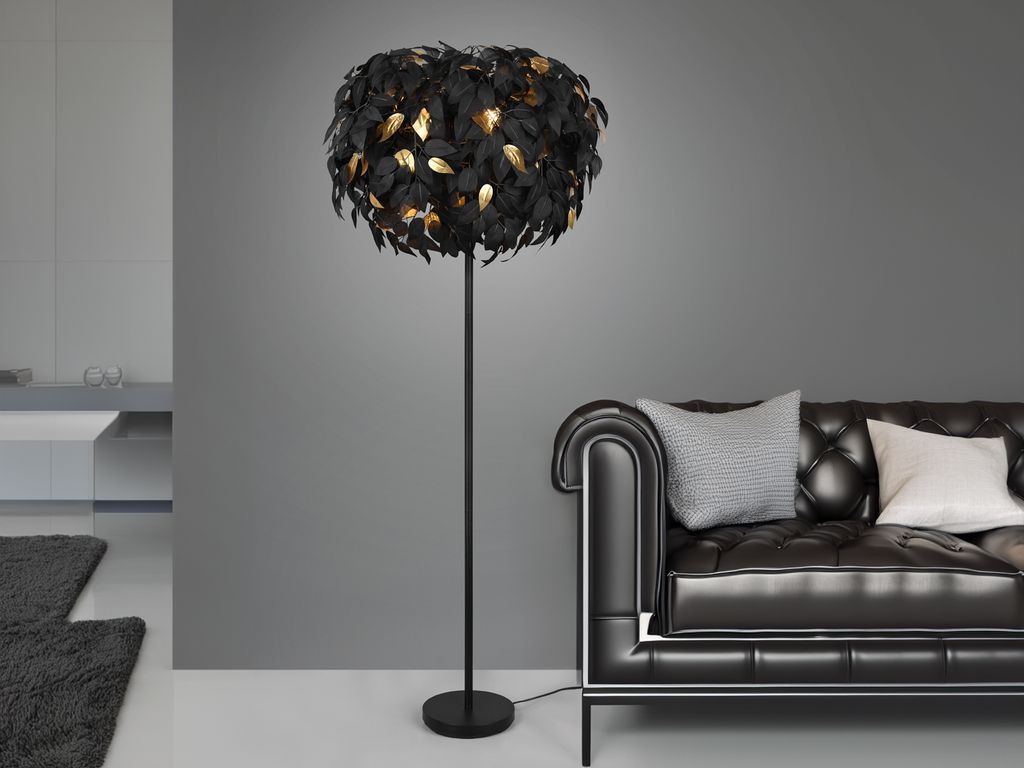 A black floor lamp with a feather-like shade is placed next to a black leather sofa in a modern living room.