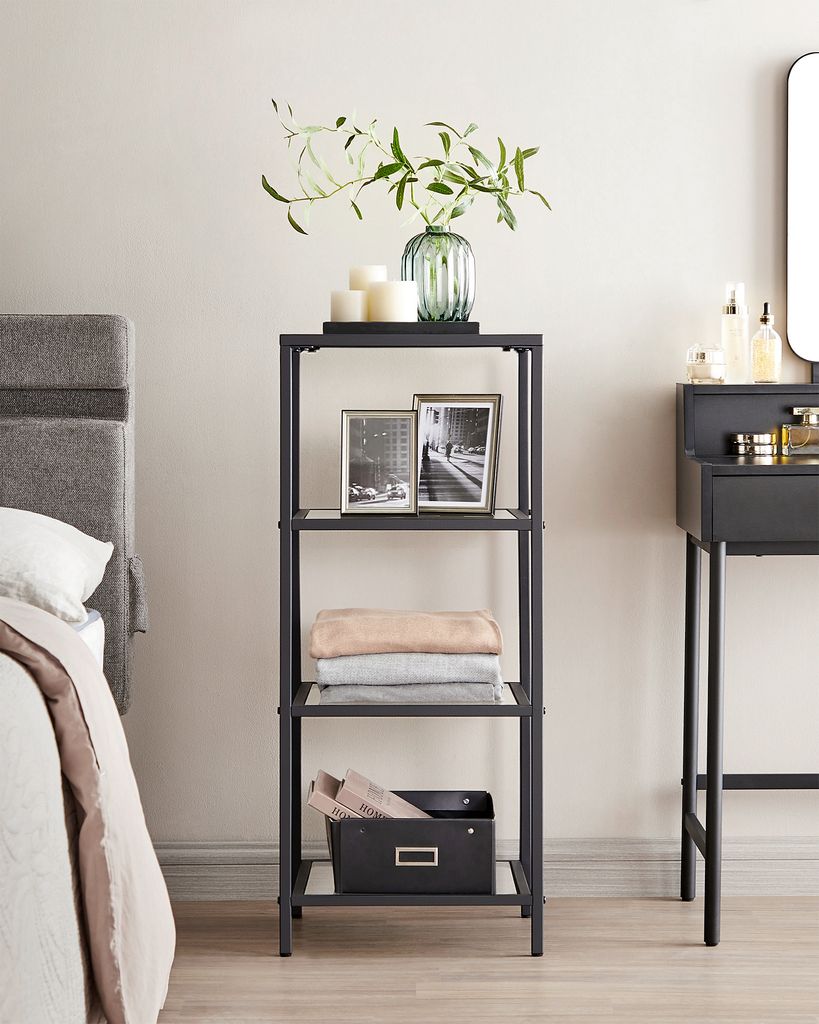 A shelf unit with decorative items next to a bed and a vanity table.