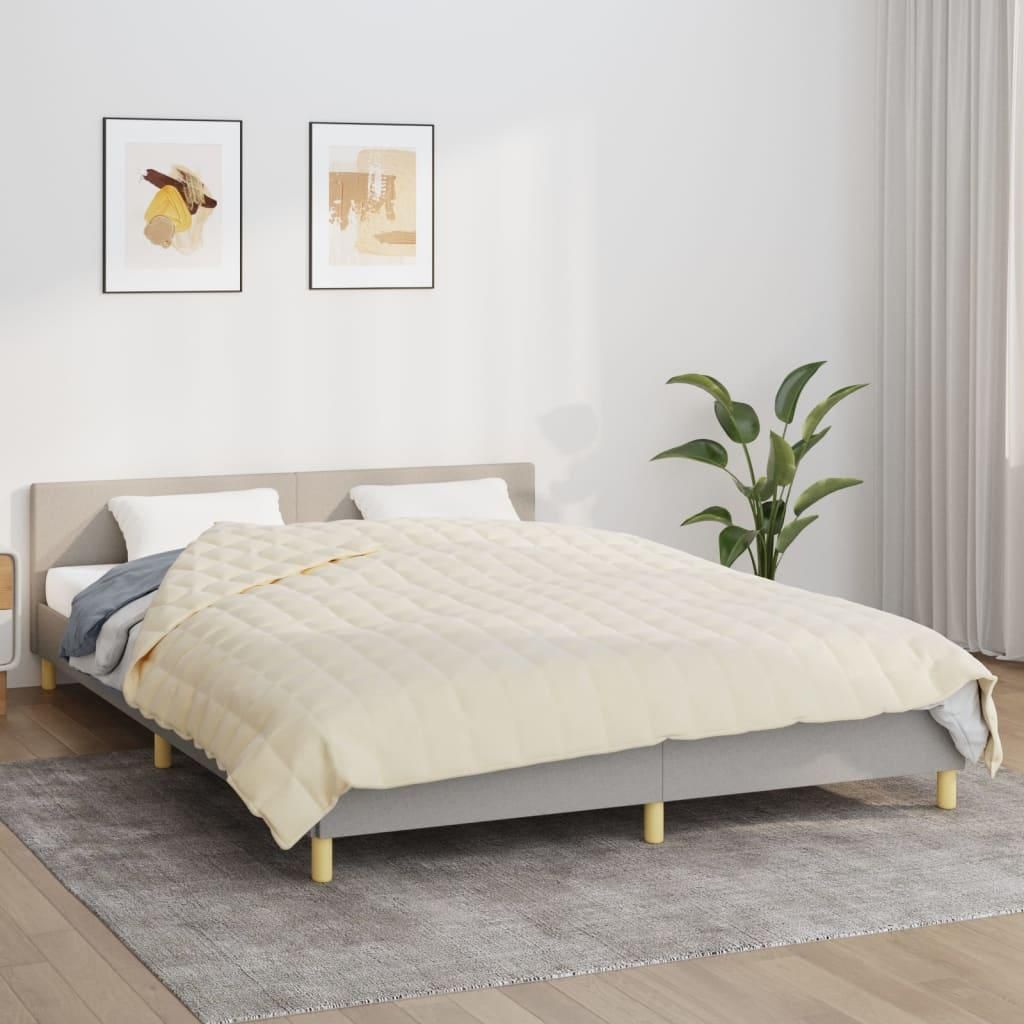 A bedroom scene with a bed, blanket, and artwork on the wall.