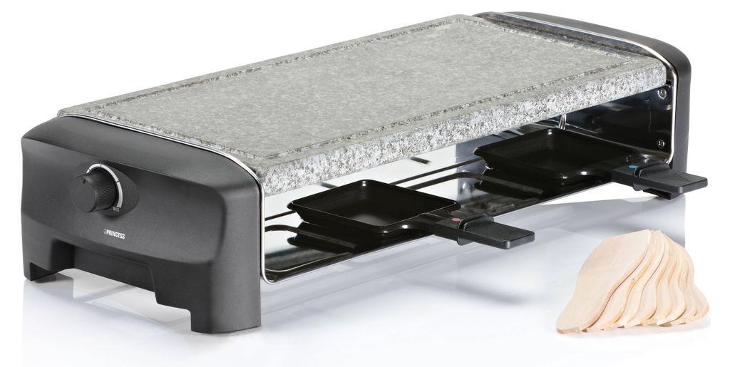 A raclette grill with a stone top and eight small pans underneath, along with a stack of wooden spatulas.