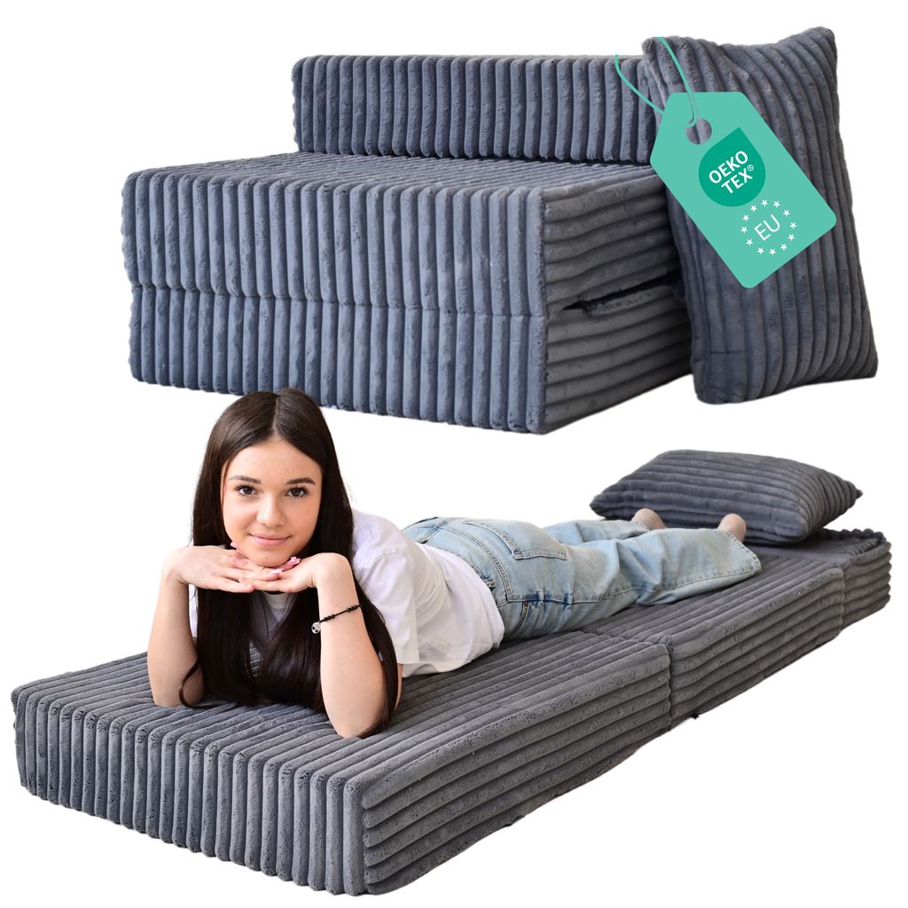A woman is lying on a folded mattress that is part of a sofa bed.