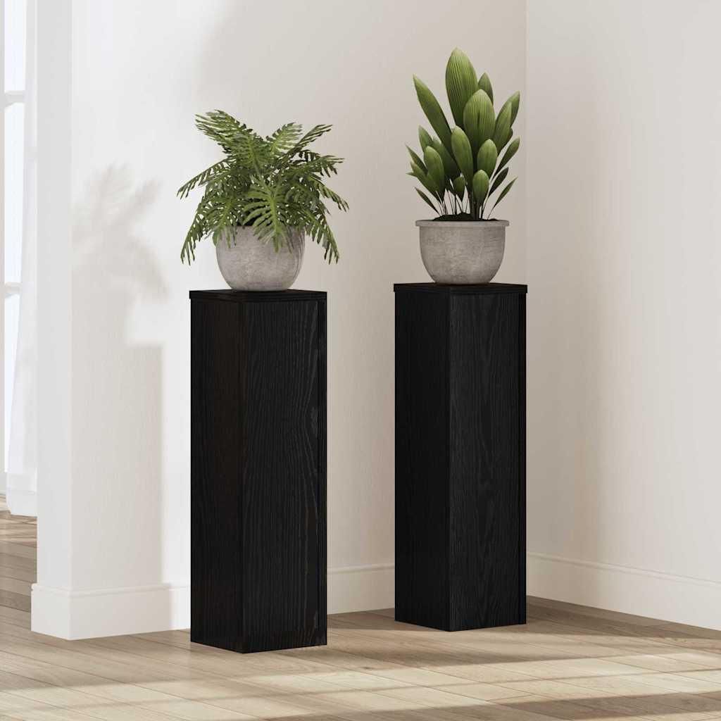 Two black plant stands with plants on top, placed in a room.