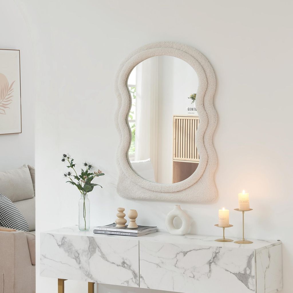 A fluffy-edged mirror is displayed above a marble-patterned console table with decorative items.