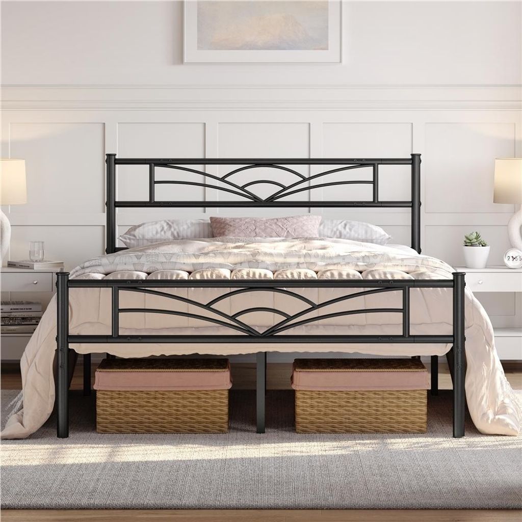 A black metal bed frame with a decorative headboard and footboard, set up in a bedroom with bedding.