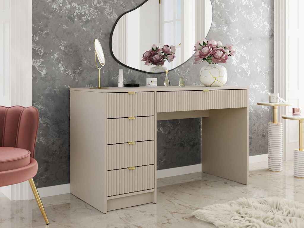 A vanity table with drawers and a mirror, set in a bedroom with a chair and side tables.