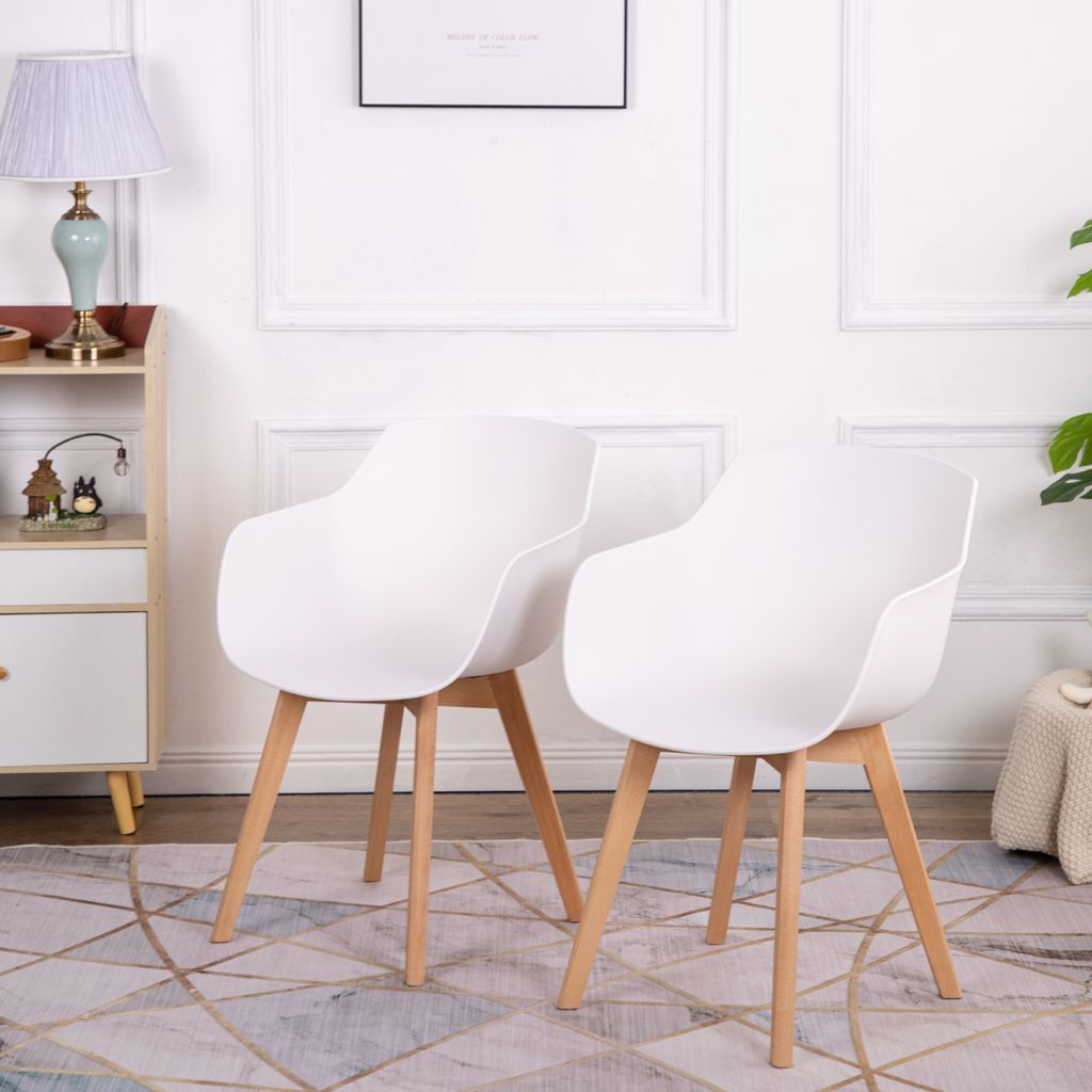 Two white chairs with wooden legs are placed on a patterned rug in a room with a lamp and a cabinet.