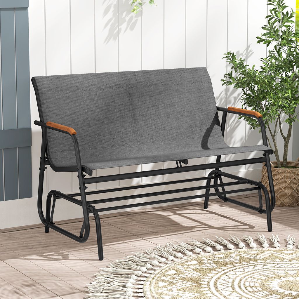 A gray fabric garden bench with black metal frame and wooden armrests sits on a wooden deck.