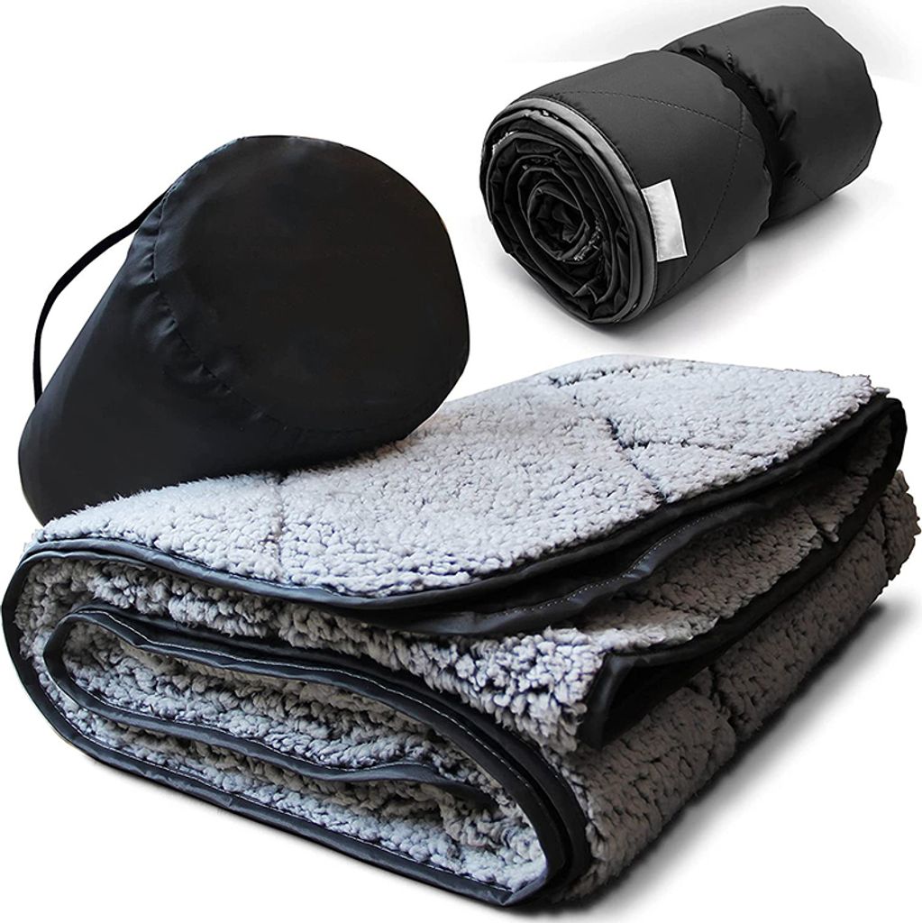 A folded camping blanket with a storage bag and a rolled-up blanket.