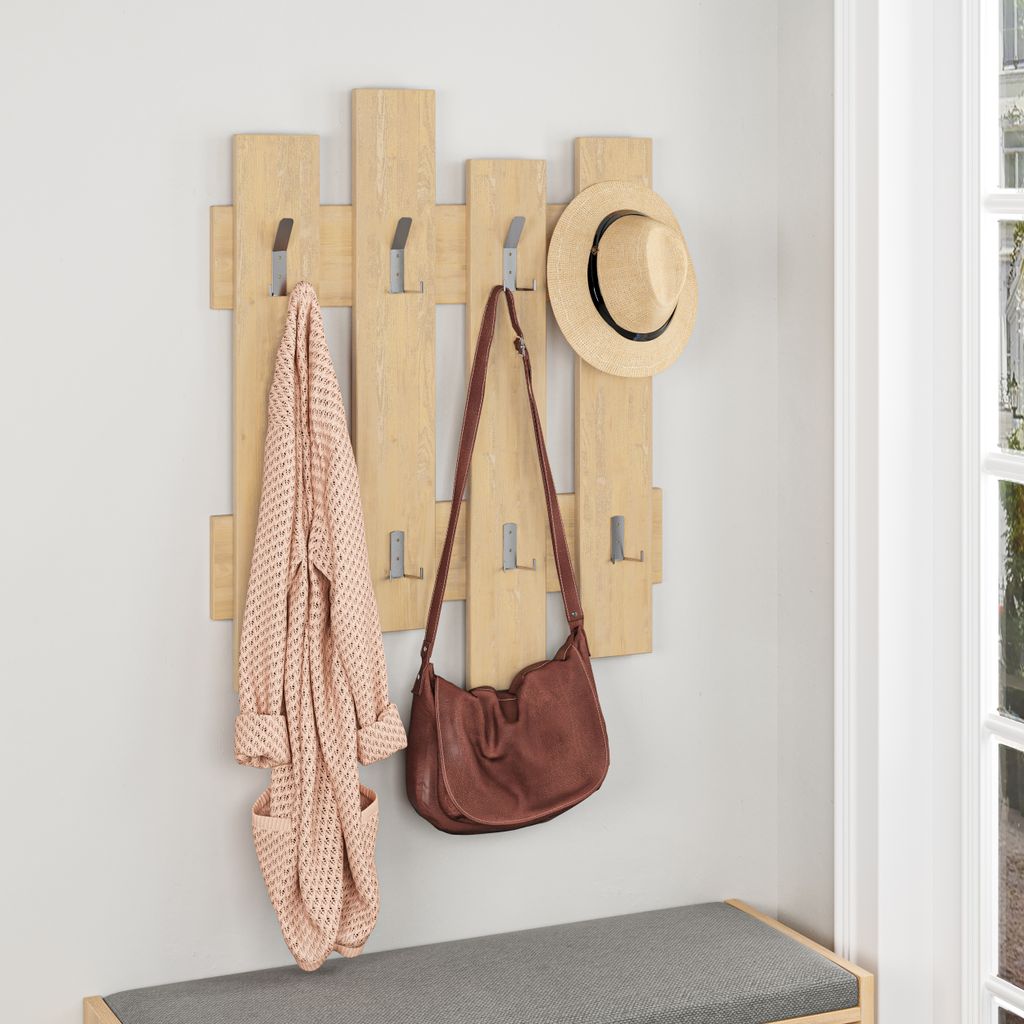 A wooden coat rack with a robe, handbag, and hat hanging on it, placed above a bench in an entryway.