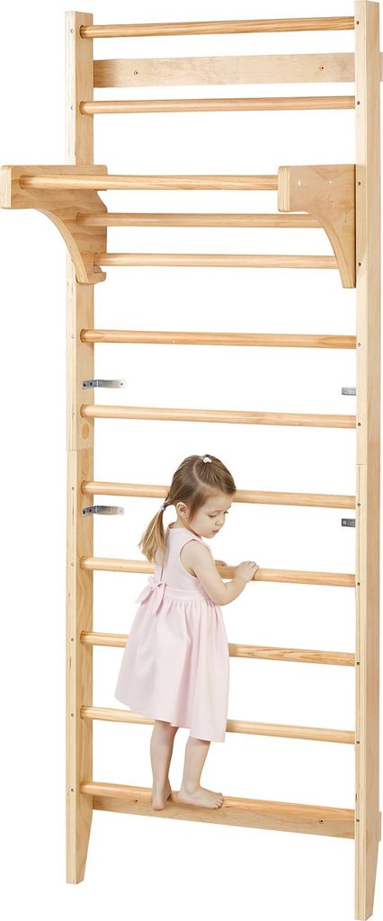 A young child is climbing on a wooden wall-mounted gym.