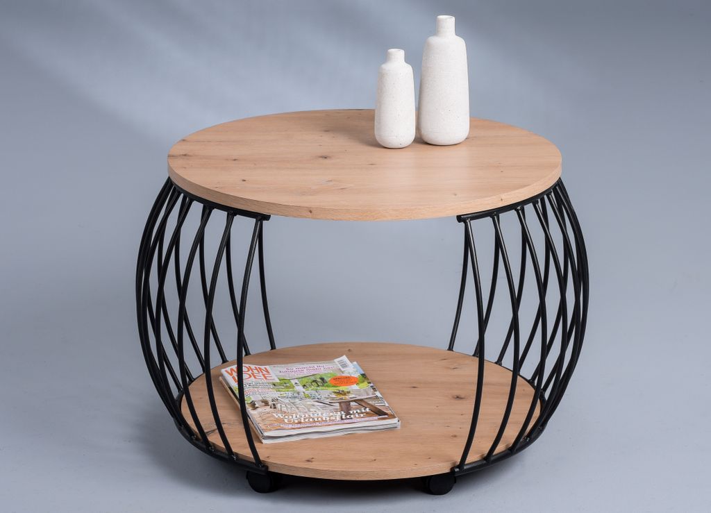 A round coffee table with a wood top and a black metal wire base, featuring two shelves. A magazine and two decorative vases are placed on the table.