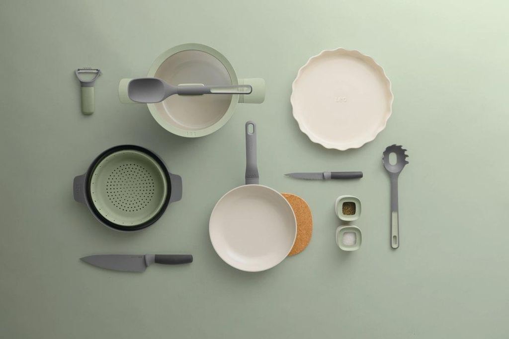 A collection of kitchenware laid out on a light green surface.