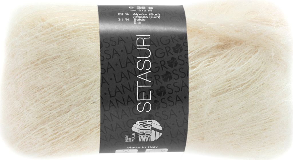 A ball of cream-colored yarn with a black label wrapped around it.