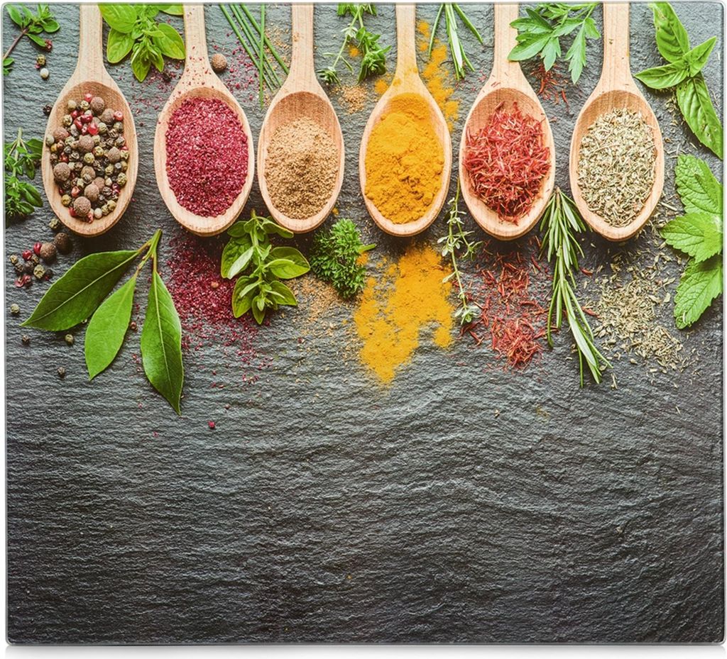 Wooden spoons filled with various spices and herbs are arranged on a dark slate surface, with some spices spilled around them.