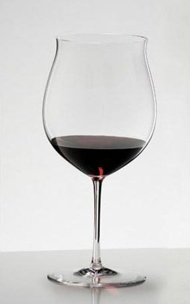 A clear studio shot of a wine glass filled with red wine.