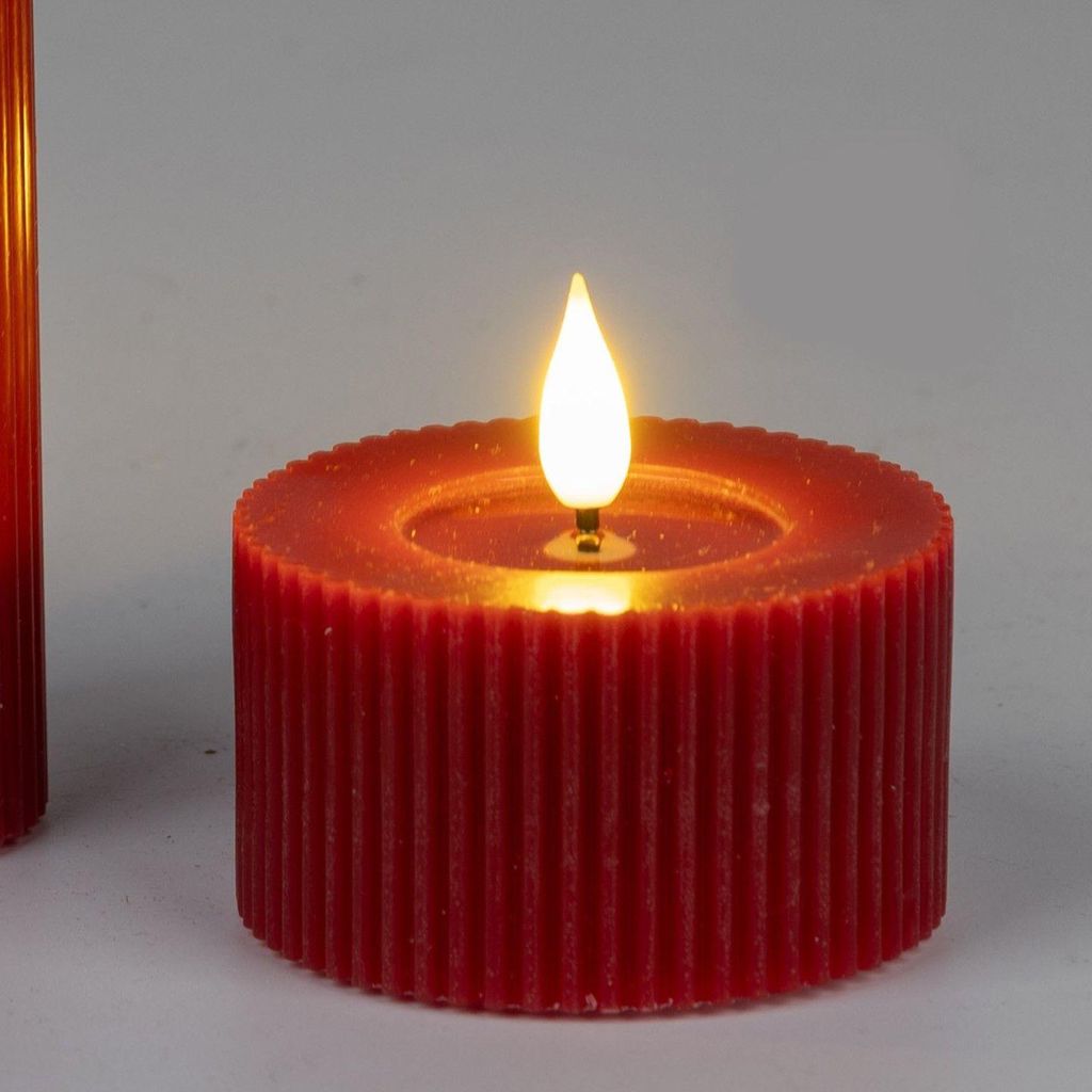 A close-up of a red LED candle with a lit flame.