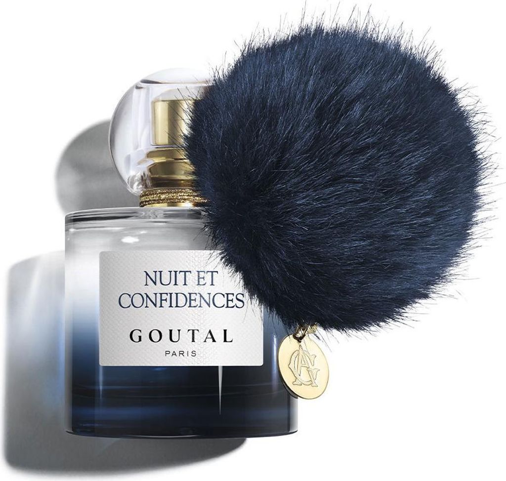 A bottle of Annick Goutal Nuit et Confidences Eau de Parfum for women, with a dark blue fluffy pom-pom attached to the neck and a gold charm.