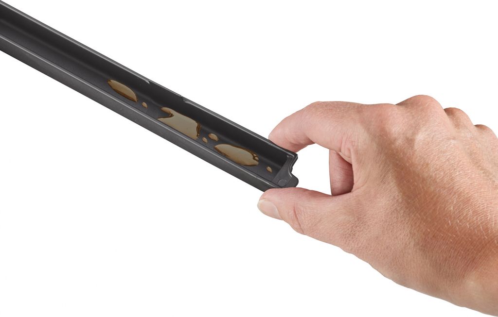 A hand holding a black vacuum sealer accessory with some liquid inside.