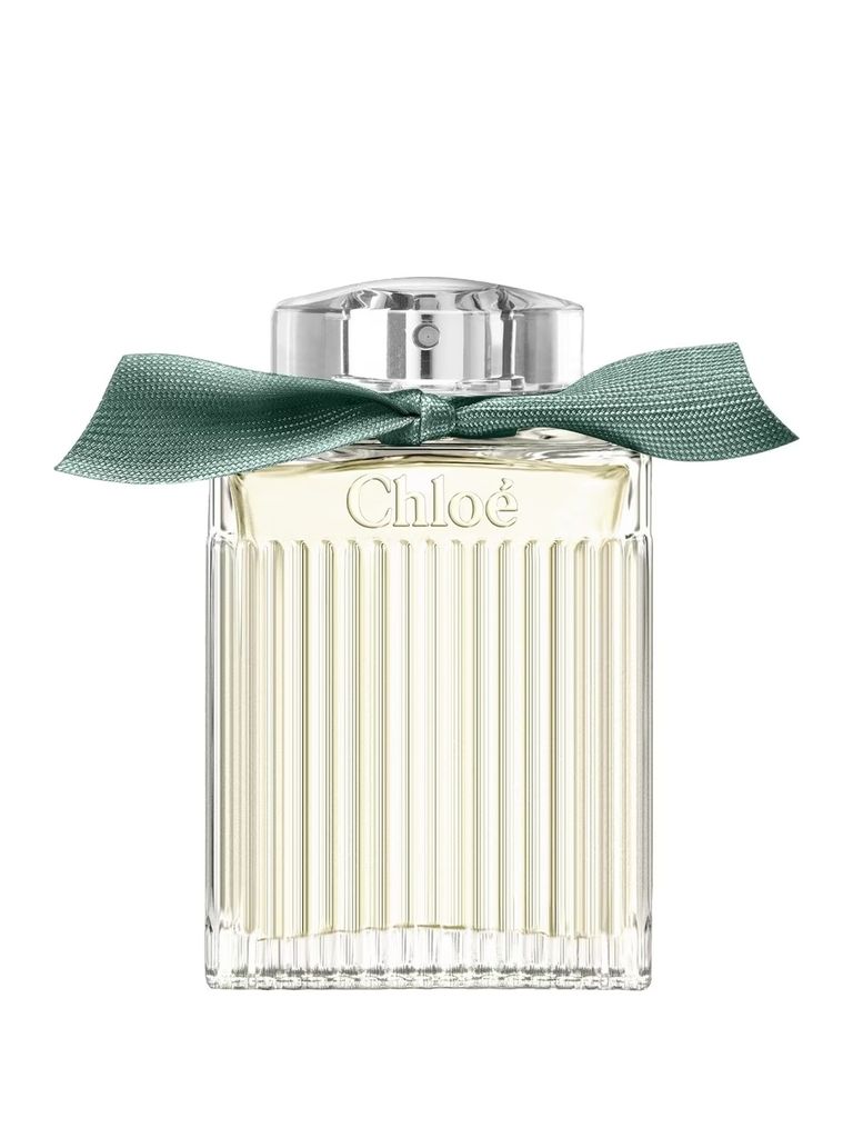 A clear, front-facing studio shot of a Chloé perfume bottle with a green ribbon tied around its neck.