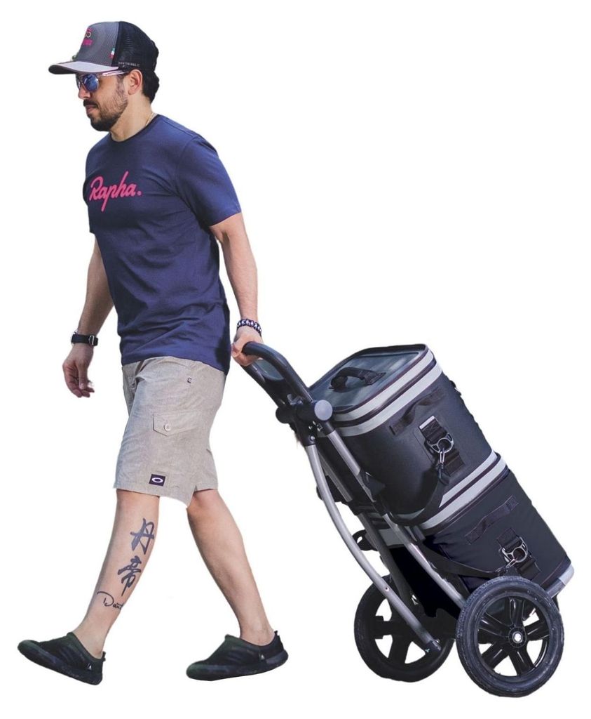 A man is pulling a shopping trolley with a cooler bag attached.