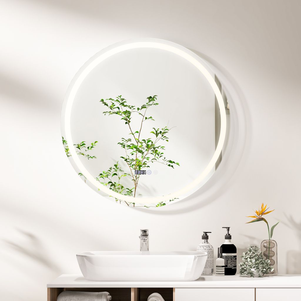 A modern bathroom vanity with a sink, faucet, and a round LED mirror reflecting a plant.