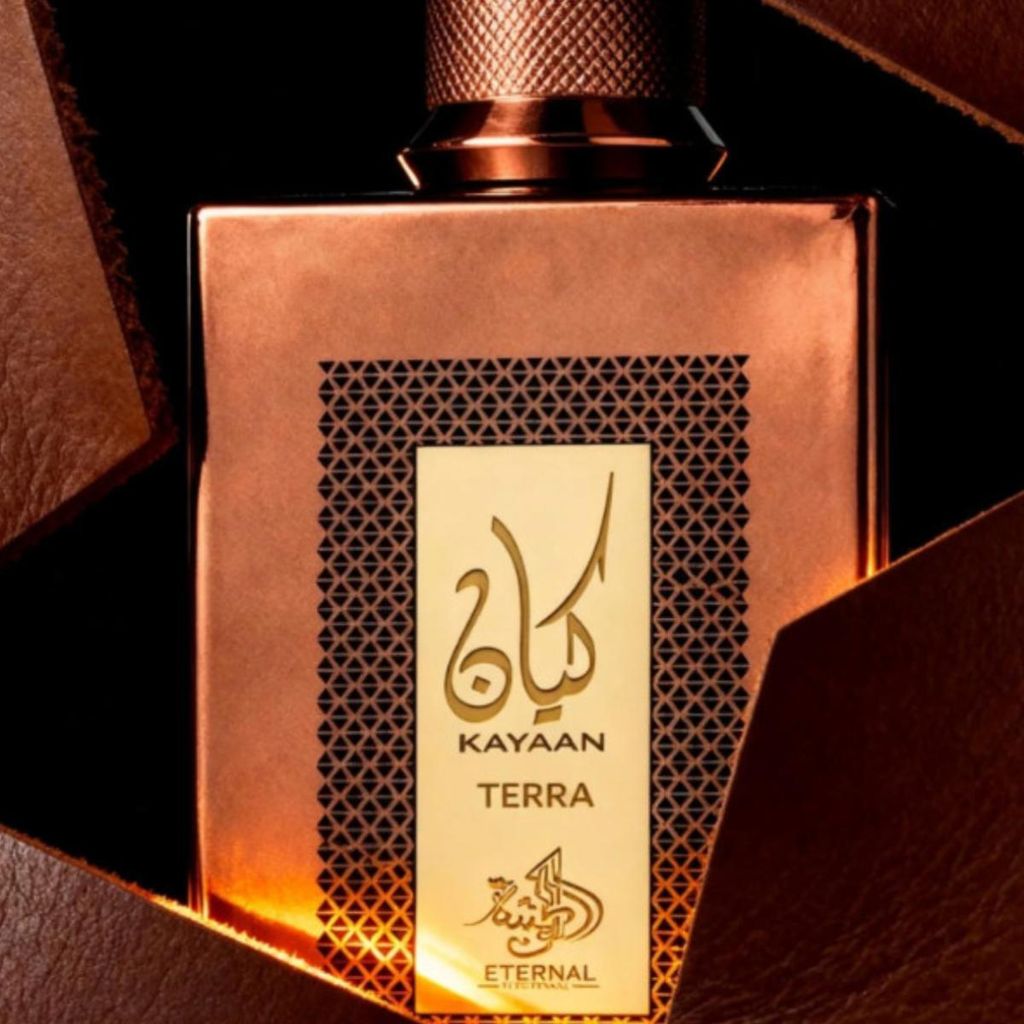 A close-up shot of a perfume bottle with a copper-colored body and a gold label with Arabic script and English text.