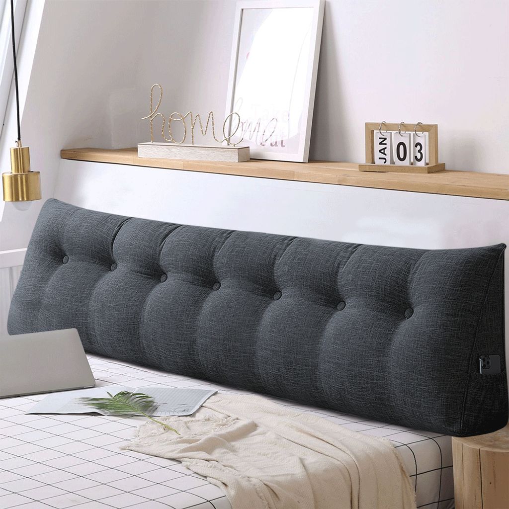 A large, tufted wedge pillow is placed on a bed.