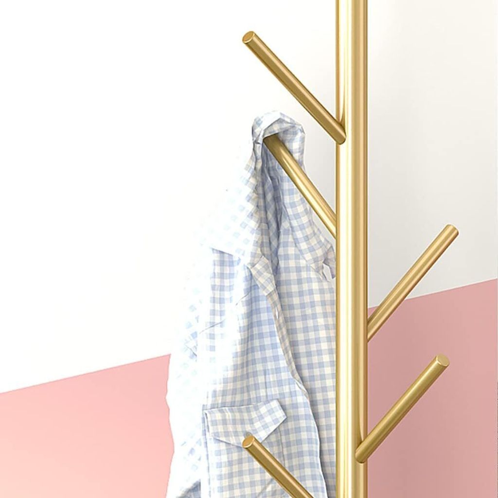 A gold coat rack with a blue and white checkered shirt hanging on it, against a white and pink background.
