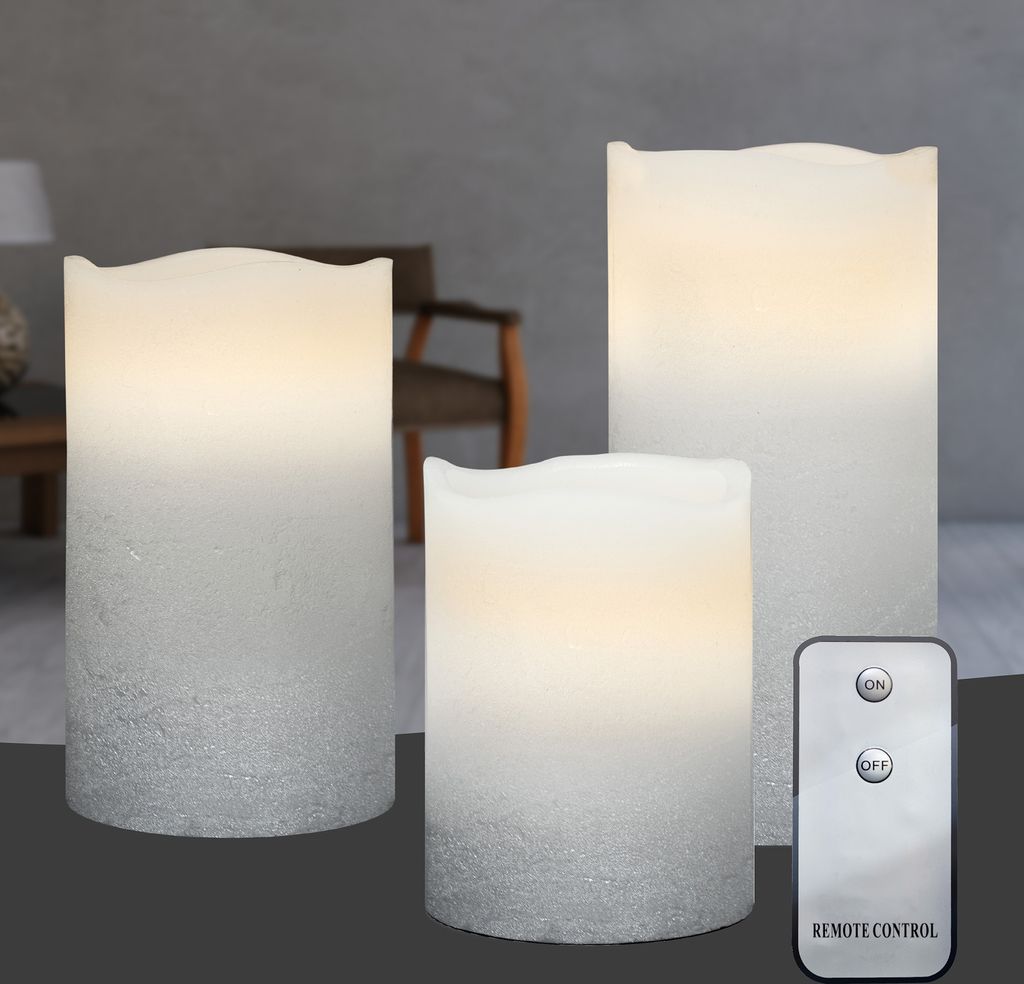 Three LED candles of varying heights are displayed on a dark surface, with a remote control in the foreground.