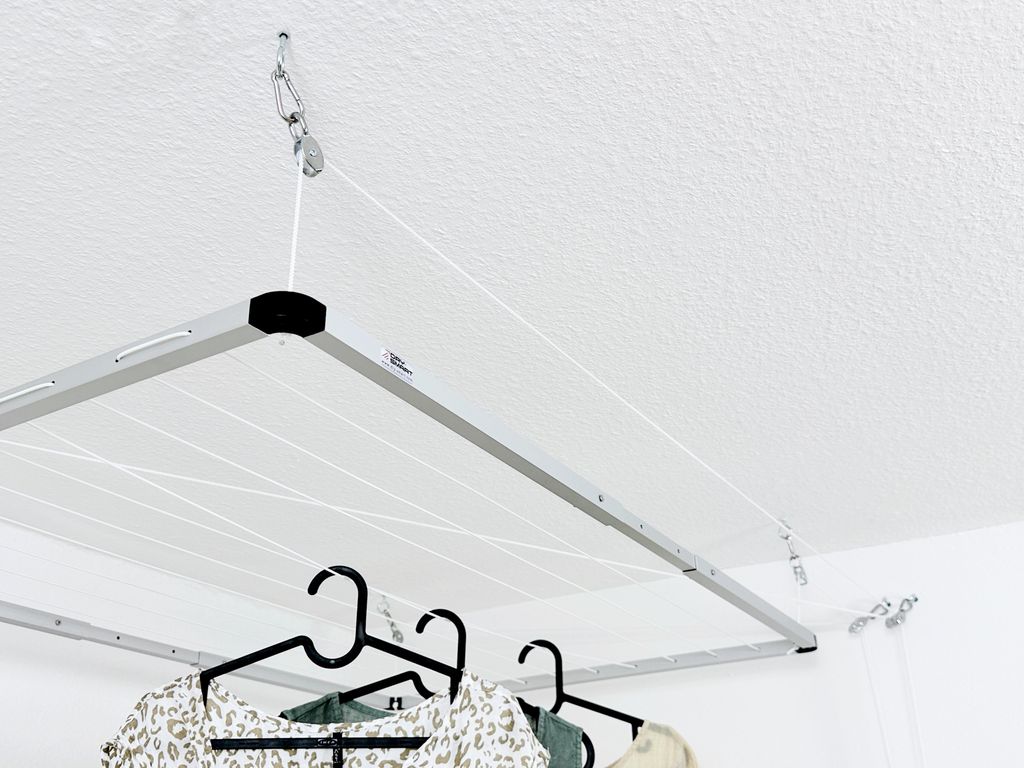 A ceiling-mounted clothes drying rack with clothes hanging on it.