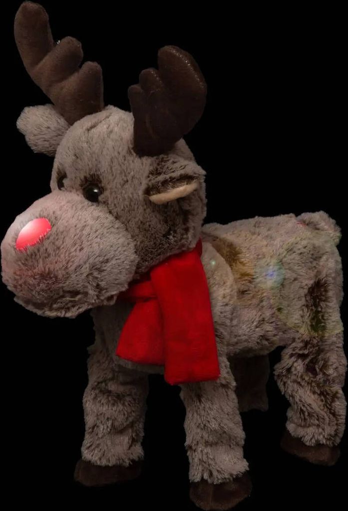 A plush reindeer toy with a red scarf and a glowing red nose, set against a black background.