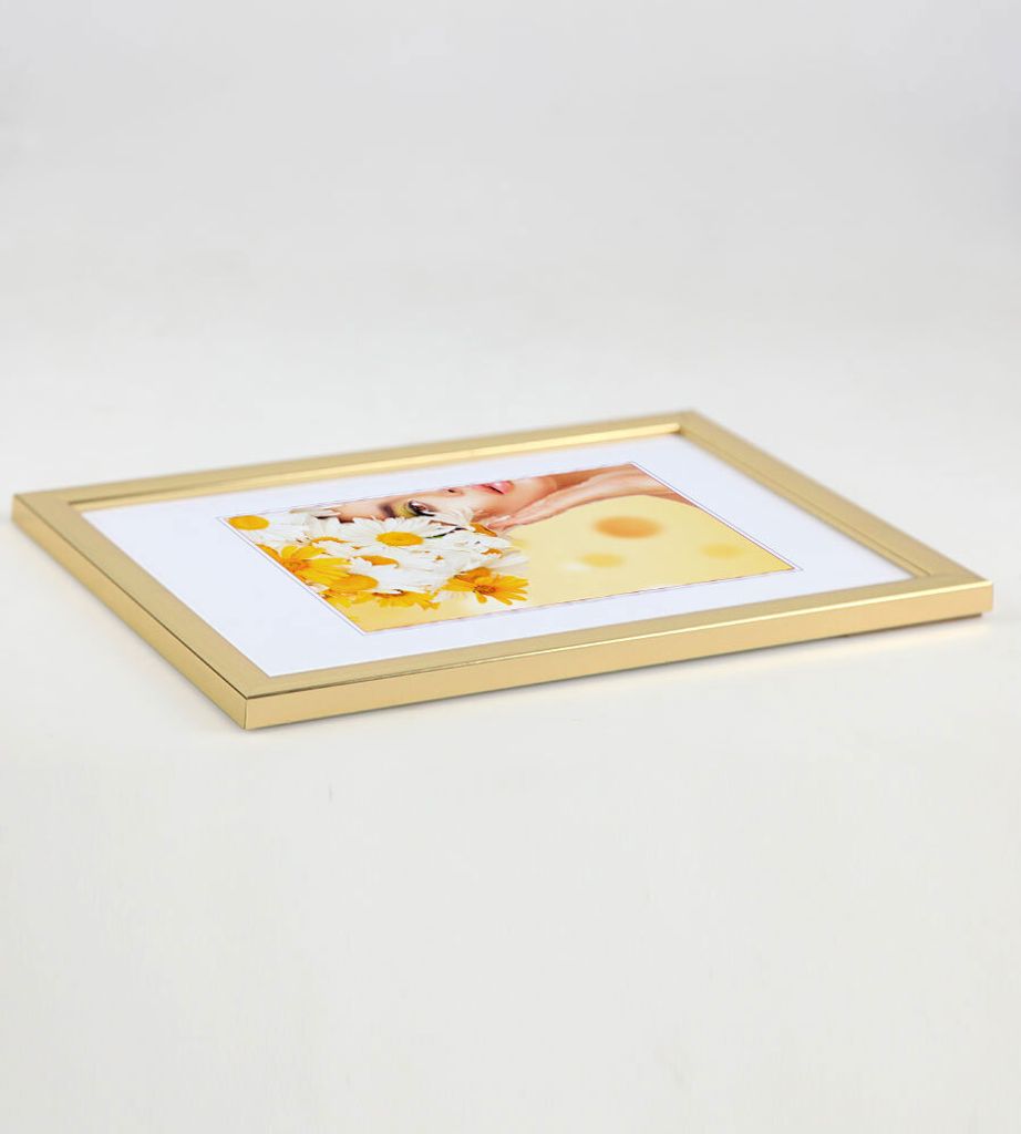 A gold picture frame with a white mat and a collage of images inside, placed on a white surface.