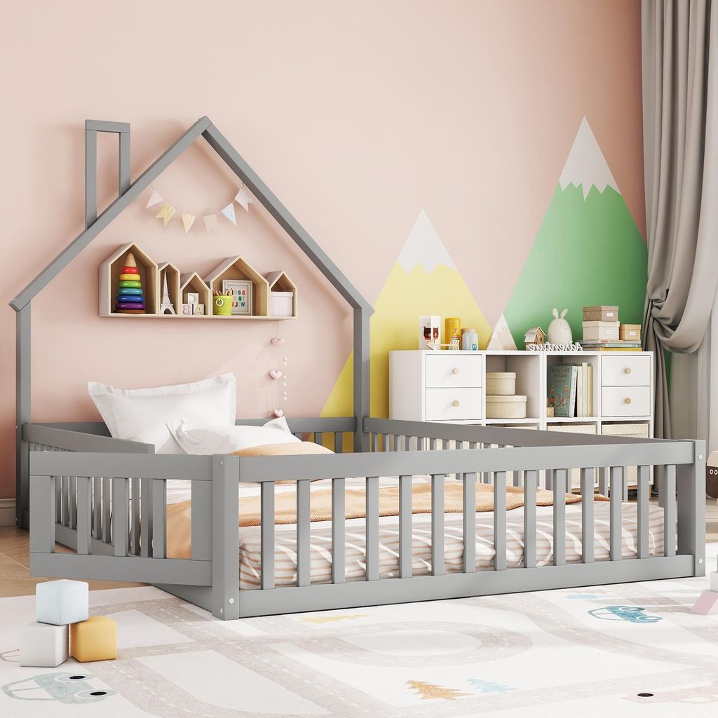 A child's bed with a house-shaped frame, decorated with a mountain mural on the wall.