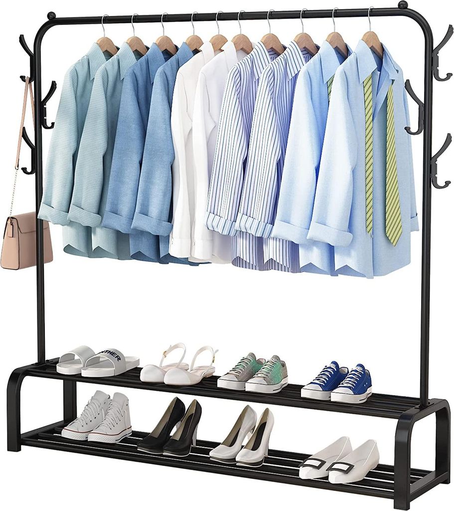A black metal garment rack with clothes hanging on it and shoes on the shelves below.