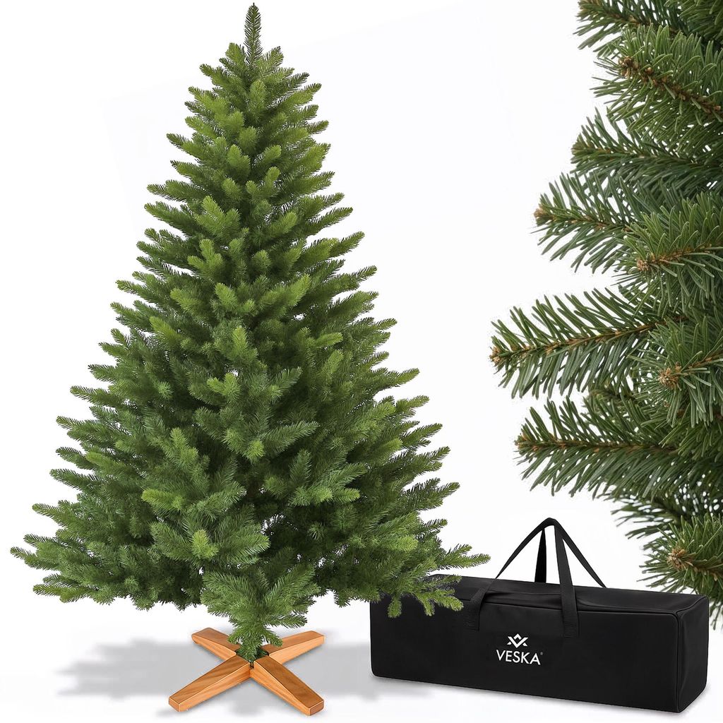 A green artificial Christmas tree with a wooden stand and a black storage bag.
