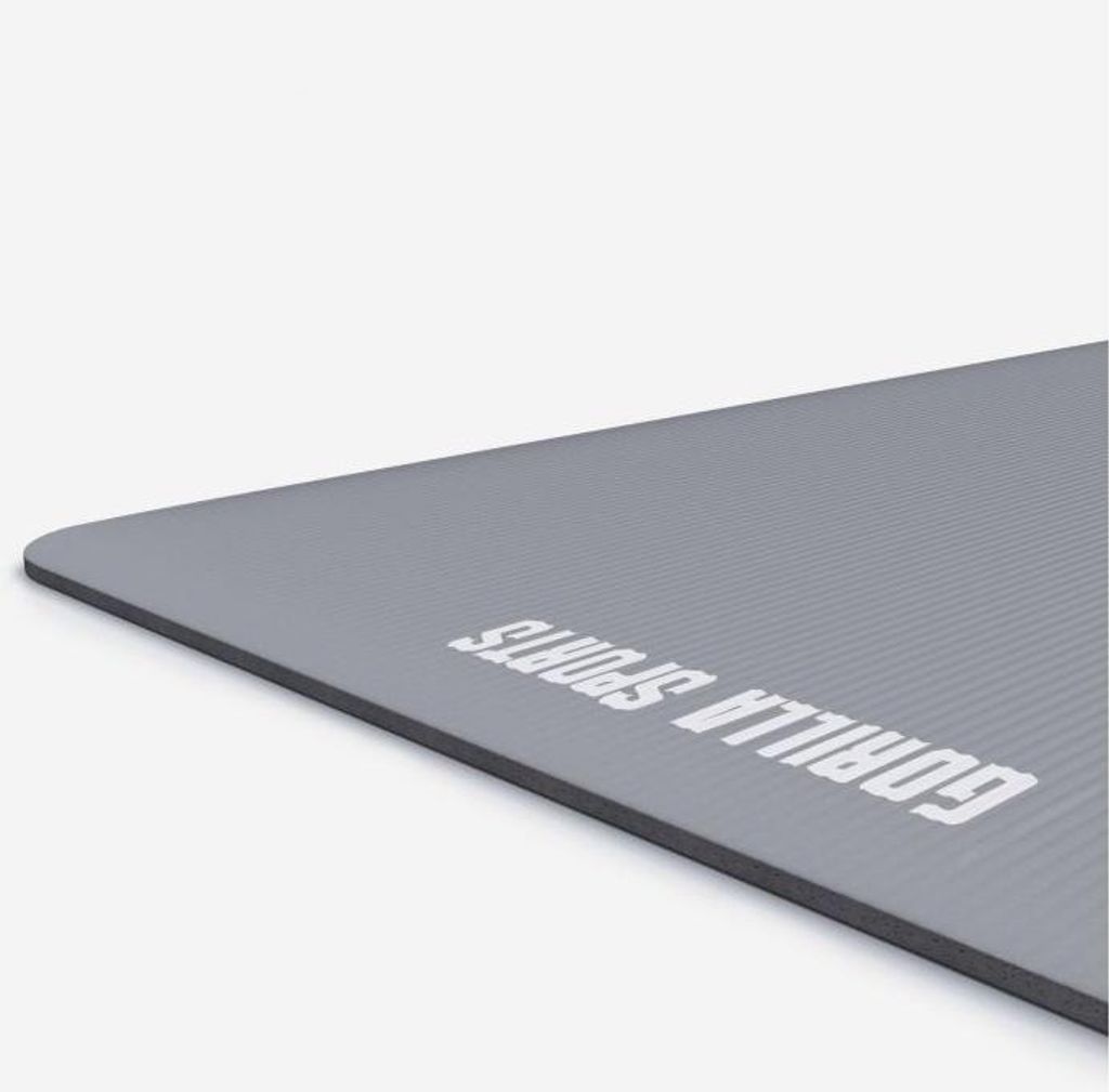 A close-up, angled view of a gray yoga mat with the brand name printed on it.