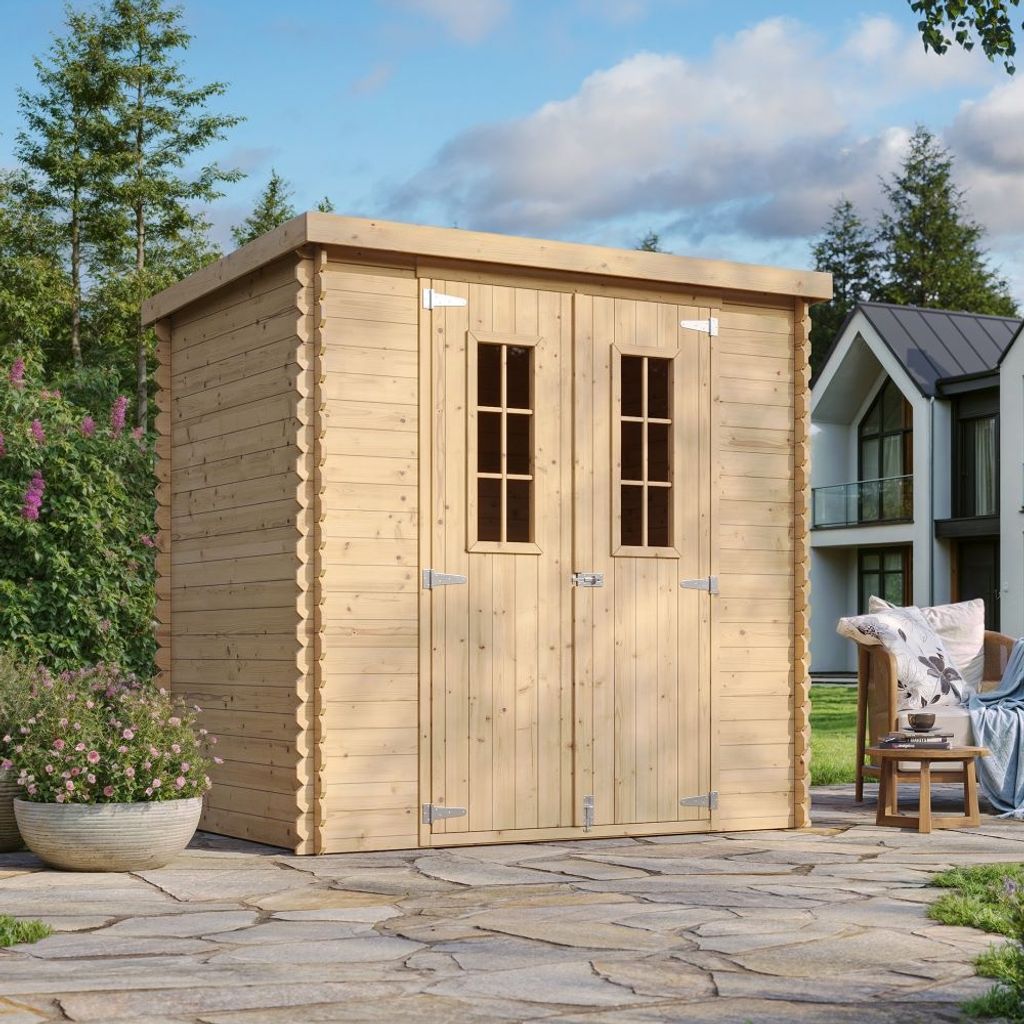 A wooden garden shed is shown in a backyard setting with a patio, plants, and a house in the background.