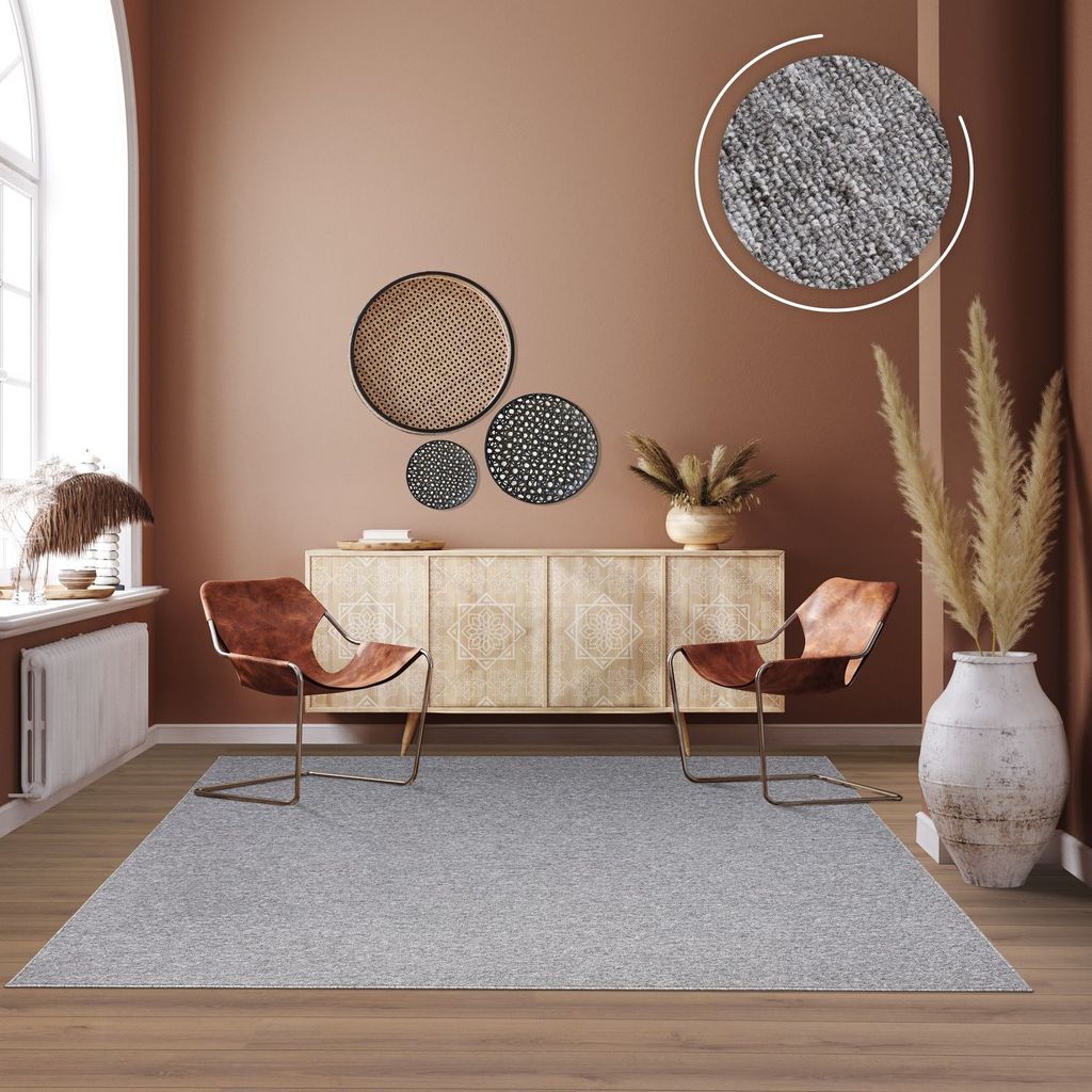 A living room scene featuring a rug, chairs, and a sideboard.