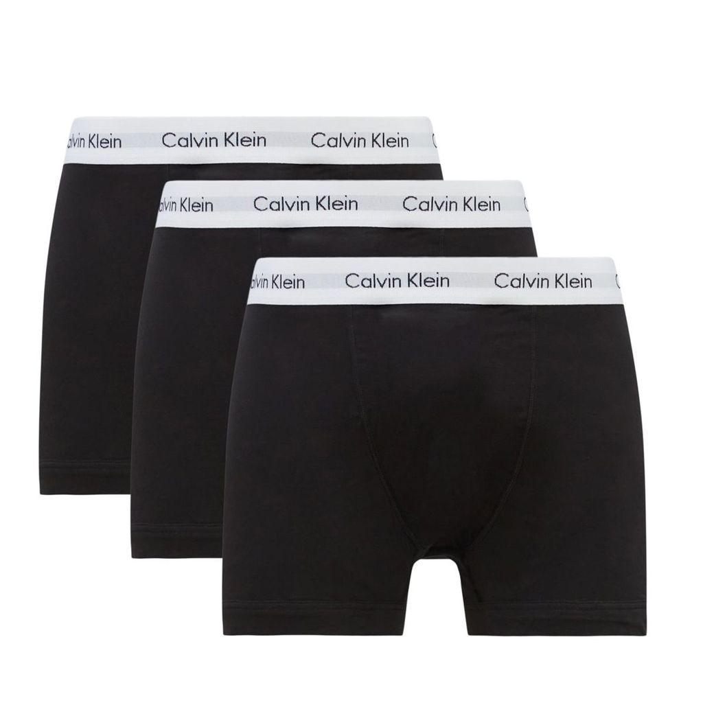 Three black Calvin Klein boxer briefs are arranged in a staggered formation against a white background.