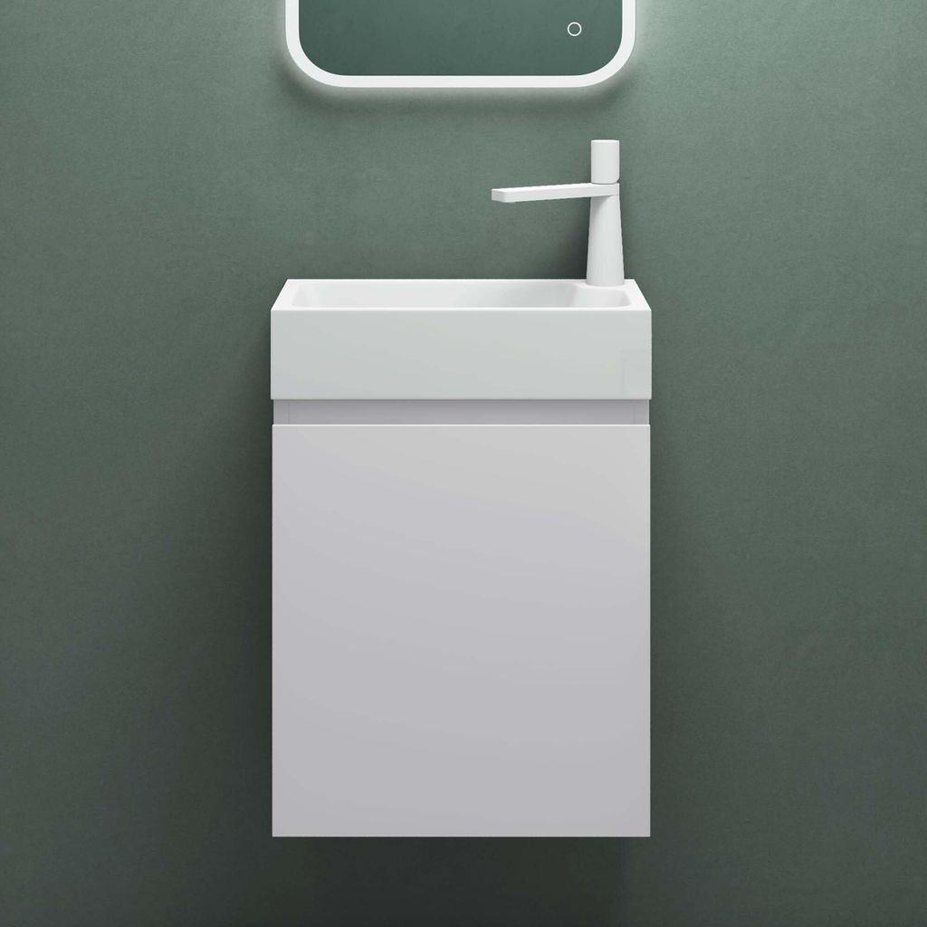 A white sink and vanity unit mounted on a green wall.