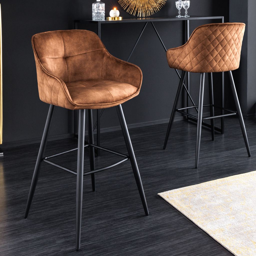 Two brown velvet bar stools are shown in a modern interior setting, with a bar counter in the background.