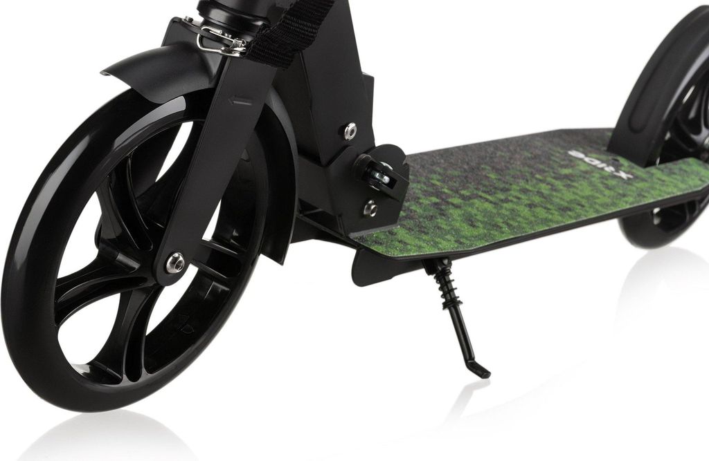 A close-up shot of a black kick scooter with a green grass-like pattern on the deck, resting on a white background.