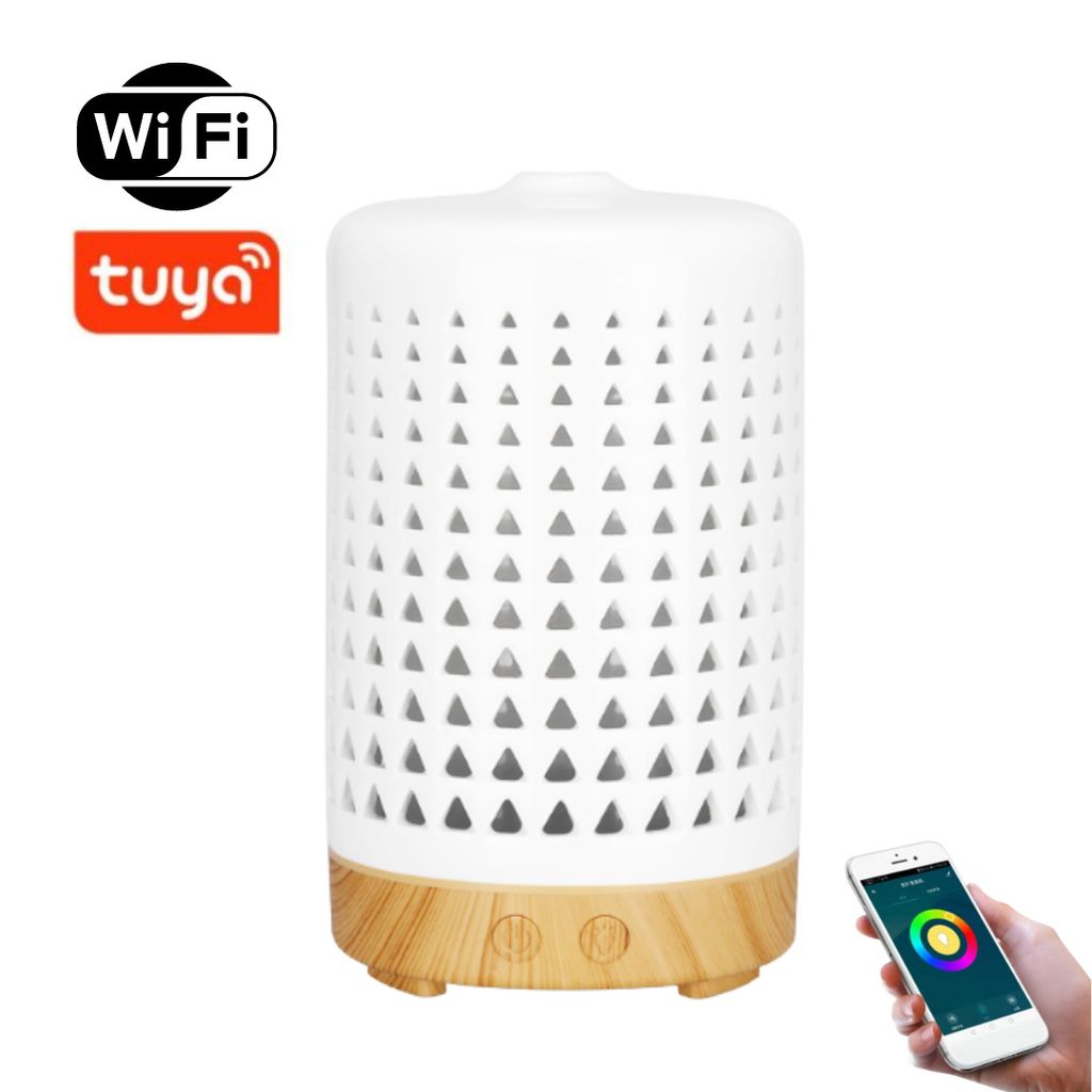A smart aroma diffuser with a white ceramic body and a light brown wooden base, shown against a white background. A smartphone displaying a color wheel is held in the lower right corner.