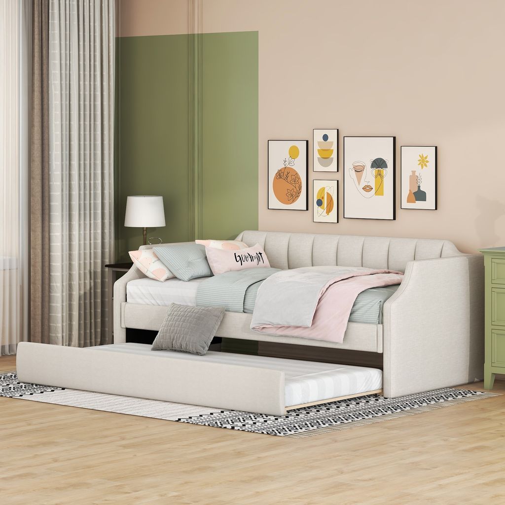 A daybed with a trundle bed pulled out, in a bedroom setting with artwork on the wall and curtains.
