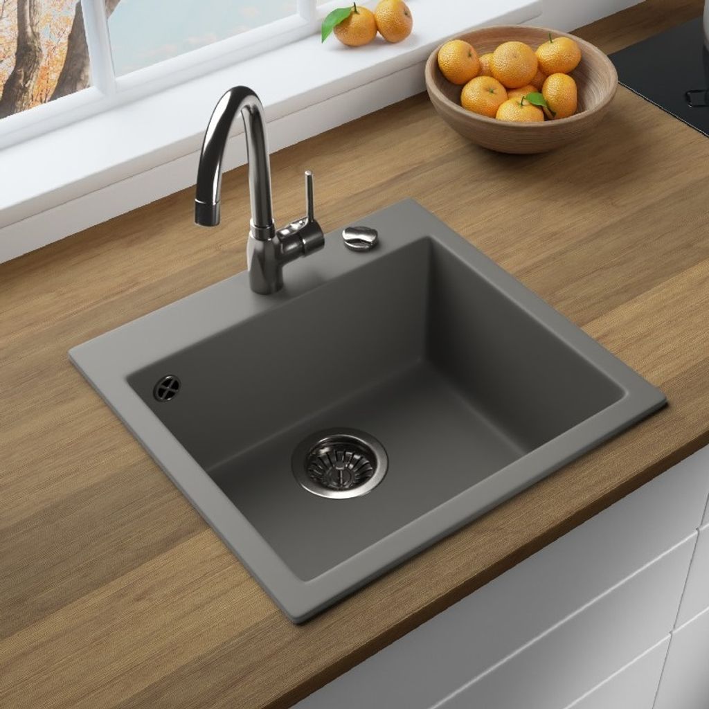 A kitchen sink with a faucet and a bowl of fruit on a wooden countertop.